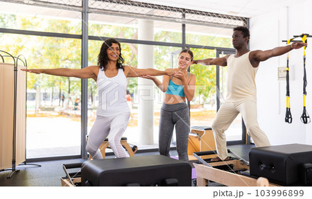 Multiracial people exercising pilates with trainer in gym 103996899