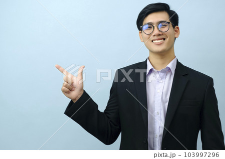 Portrait of businessman pointing and looking at camera. 103997296