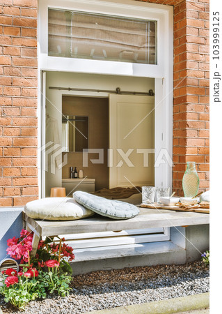 an outside area with flowers and pillows on the window sies, in front of a brick building that is being used as a 103999125