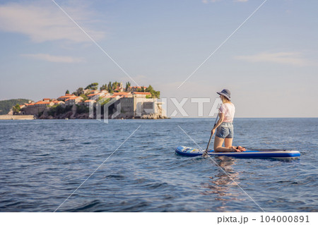 Young women Having Fun Stand Up Paddling in blue water sea near st stefan island in Montenegro. SUP 104000891