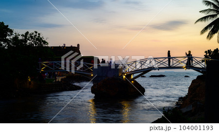 Galle butterfly bridge in Dharmapala park evening sunset, long exposure landscape shot. People taking photographs on the bridge. Galle butterfly bridge in Dharmapala park evening sunset, long exposure landscape shot. People taking photographs on the bridge. 104001193