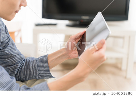 自宅のリビングでタブレットを操作する若い男性 自宅のリビングでタブレットを操作する若い男性 104001290