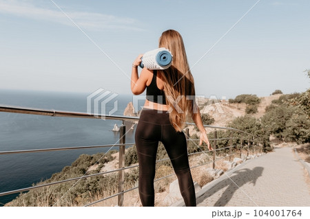 Fitness woman sea. Outdoor workout on yoga mat roller in park near to ocean beach. Female fitness pilates yoga routine concept. Healthy lifestyle. Happy fit woman exercising with rubber band in park. Fitness woman sea. Outdoor workout on yoga mat roller in park near to ocean beach. Female fitness pilates yoga routine concept. Healthy lifestyle. Happy fit woman exercising with rubber band in park. 104001764
