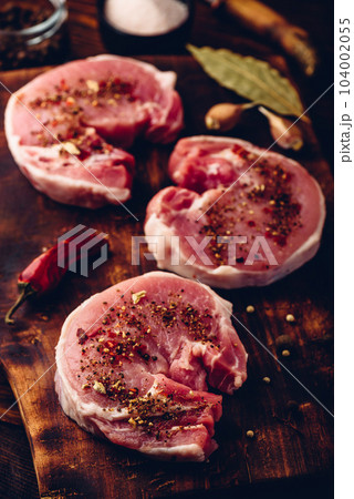 Pork loin steaks with ground spices on cutting board Pork loin steaks with ground spices on cutting board 104002055