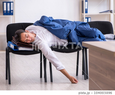 Young male employee sleeping in the office on chairs Young male employee sleeping in the office on chairs 104003896