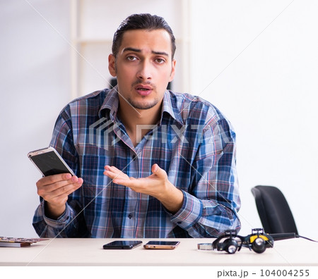 Young handsome technician repairing mobile phone Young handsome technician repairing mobile phone 104004255