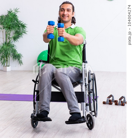 Young man in wheel-chair doing exercises indoors Young man in wheel-chair doing exercises indoors 104004274