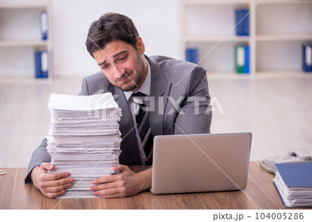 Young male employee and too much work in the office 104005286