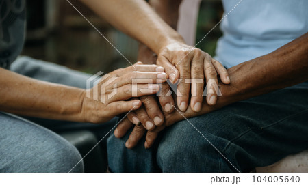 Hands of the old man and a woman hand on the wood table Hands of the old man and a woman hand on the wood table 104005640