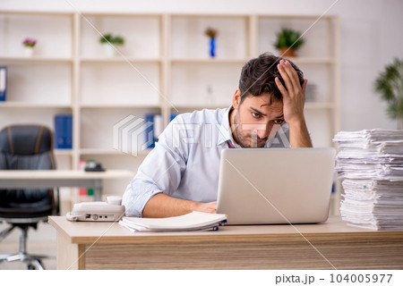 Young male employee and too much work in the office Young male employee and too much work in the office 104005977