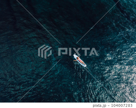 Aerial drone view with surfer girl in blue ocean. Surfing mood 104007283