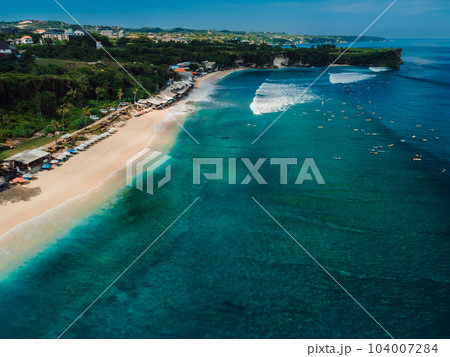 Popular holiday beach in Bali with surfing waves in turquoise ocean. Aerial view Popular holiday beach in Bali with surfing waves in turquoise ocean. Aerial view 104007284