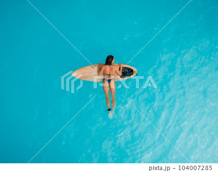 Surfgirl in bikini on surfboard in blue or turquoise ocean. Aerial view of sexy surfer woman 104007285