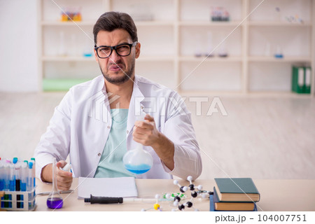 Young male chemist sitting at the lab Young male chemist sitting at the lab 104007751