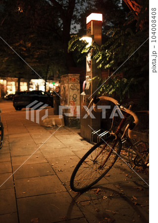 Vertical view of a bicycle parked on the sidewalk in the evening 104008408
