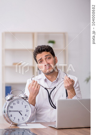 Young male doctor in time management concept Young male doctor in time management concept 104008682