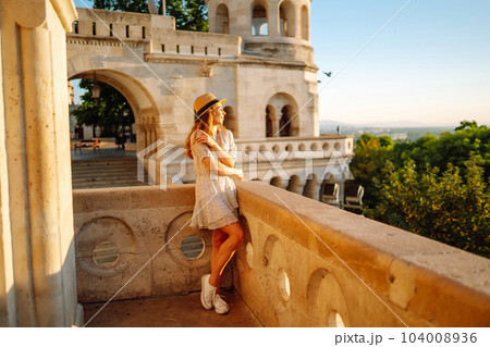 Portrait of happy tourist in hat at dawn enjoys cityscape. Traveling in Europe. Concept tourism. Portrait of happy tourist in hat at dawn enjoys cityscape. Traveling in Europe. Concept tourism. 104008936