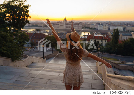 Young female tourist enjoys view of city at sunset. back view Lifestyle, travel, nature, active life 104008956