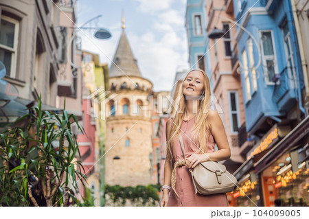 Portrait of beautiful woman tourist with view of Galata tower in Beyoglu, Istanbul, Turkey. Turkiye 104009005