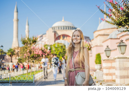 Woman enjoy beautiful view on Hagia Sophia Cathedral, famous islamic Landmark mosque, Travel to Istanbul, Turkey. Sunny day architecture and Hagia Sophia Museum, in Eminonu, istanbul, Turkey. Turkiye 104009129