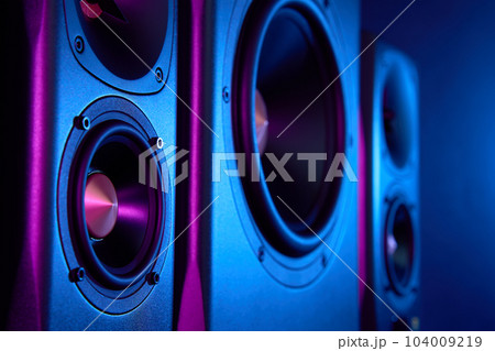 Multimedia acoustic sound speakers with neon lighting. Sound audio system with two satellites and subwoofer on dark background. Multimedia acoustic sound speakers with neon lighting. Sound audio system with two satellites and subwoofer on dark background. 104009219