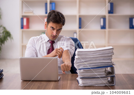 Young male employee and too much work in the office 104009681