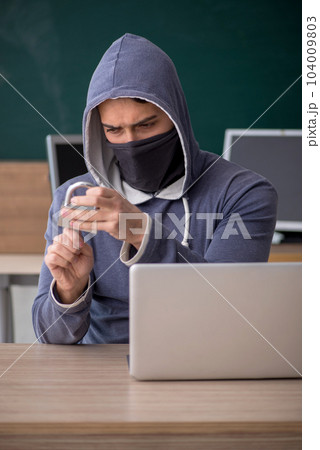Young male hacker sitting in the classroom Young male hacker sitting in the classroom 104009803