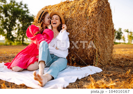 Two young women having fun near haystack. Fashion concept. Summer concept. 104010167