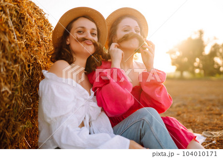 Two young women having fun near haystack. Fashion concept. Summer concept. 104010171