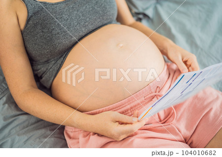 A pregnant woman looks at the results of a blood test printed on paper 104010682