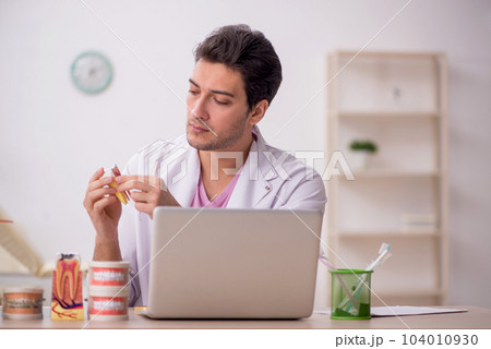 Young male dentist working in the clinic 104010930