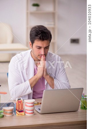 Young male dentist working in the clinic 104010933