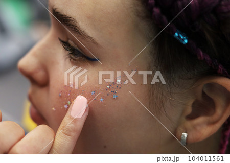 a girl with brown hair and pigtails braided into a pigtail of artificial hair. The process of applying makeup 104011561