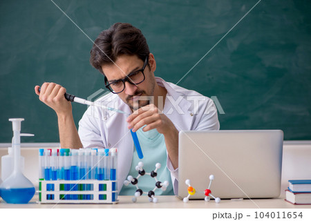 Young male chemist in front of blackboard 104011654