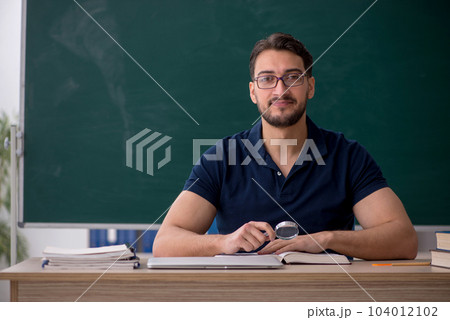 Young male teacher sitting in the classroom 104012102