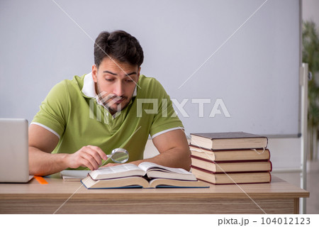 Young male student sitting in front of whiteboard Young male student sitting in front of whiteboard 104012123