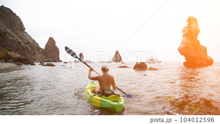 Woman kayak sea. Happy tourist takes sea photo in kayak canoe for memory. Woman traveler poses amidst volcanic mountains during adventurous journey in kayak. Woman kayak sea. Happy tourist takes sea photo in kayak canoe for memory. Woman traveler poses amidst volcanic mountains during adventurous journey in kayak. 104012596
