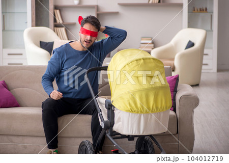 Young man looking after newborn at home 104012719