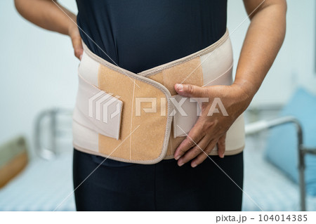 Asian lady patient wearing back pain support belt for orthopedic