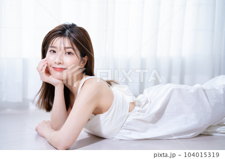 フローリングに寝転ぶ若い女性 フローリングに寝転ぶ若い女性 104015319
