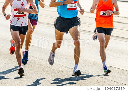four athlete runners running marathon race in city road, numbers on shirts, summer sports games four athlete runners running marathon race in city road, numbers on shirts, summer sports games 104017859