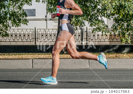 side view female runner athlete running city marathon race, summer sports games 104017863