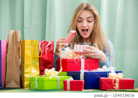 Happy girl opening box with gift and smiling 104019616