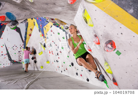 Woman climbing artificial rock in gym 104019708