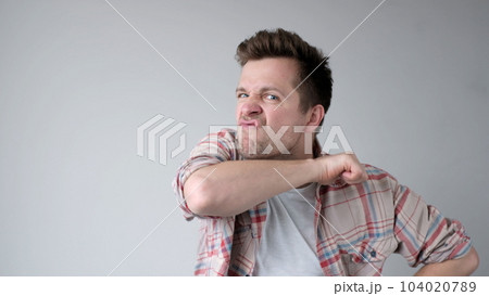 European young man behaves aggressively, contorts an angry face, and threatens someone 104020789
