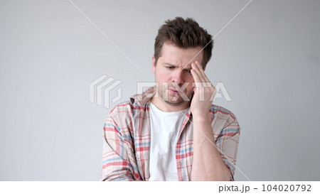 The European young man suffers from a headache and rubs his temples. 104020792
