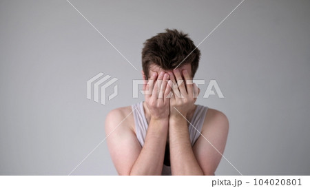 The tired European young man, lacking energy, closes his face with hands. He has no positive emotions The tired European young man, lacking energy, closes his face with hands. He has no positive emotions 104020801