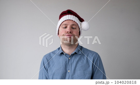 The sad and sorrowful European young man in a New Year's hat looks gloomily into the camera. Disappointments in the New Year celebration 104020818