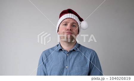 The sad and sorrowful European young man in a New Year's hat looks gloomily into the camera. Disappointments in the New Year celebration 104020819