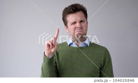 European young man shakes his head in disagreement and says no, pointing his finger upwards European young man shakes his head in disagreement and says no, pointing his finger upwards 104020846